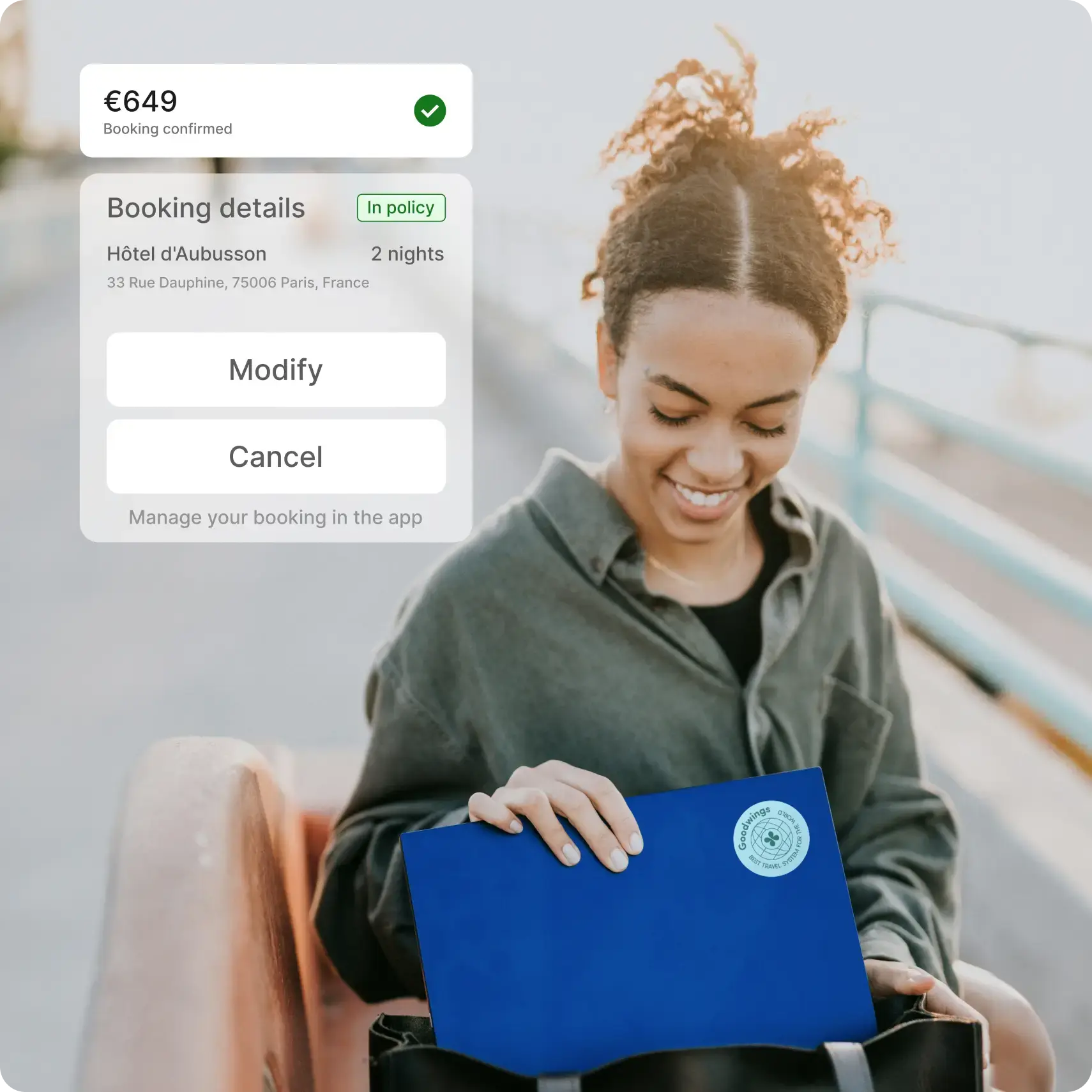 A business traveler sitting on a bench, smiling while looking at a blue document folder in her bag. A booking confirmation overlay displays hotel details and options to modify or cancel.